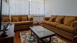 A living room with two sofas, a coffee table, and a television. - Apto a 700m da Praia do Leblon com Wi-fi e ar (Rio de Janeiro)