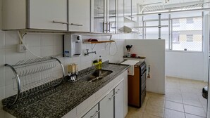 A kitchen with white cabinets, a granite countertop, a built-in oven, and a window with a view. - Apto a 700m da Praia do Leblon com Wi-fi e ar (Rio de Janeiro)