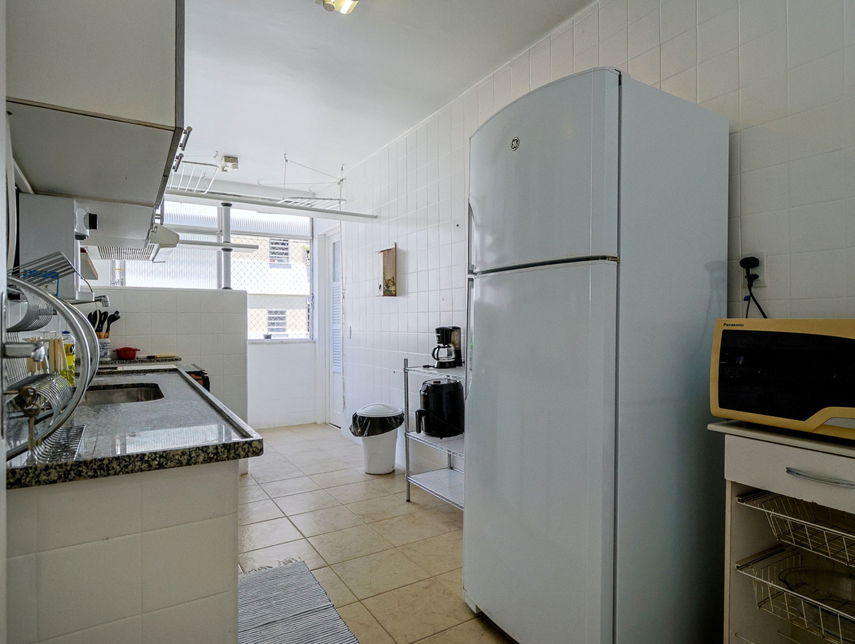 A kitchen with white cabinets, a refrigerator, a coffee maker, and a sink.