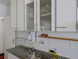 A kitchen with white cabinets, a granite countertop, a stainless steel sink, and a dish rack. - Apto a 700m da Praia do Leblon com Wi-fi e ar (Rio de Janeiro)