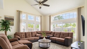 A spacious living room with a sectional sofa, a coffee table, and a ceiling fan.