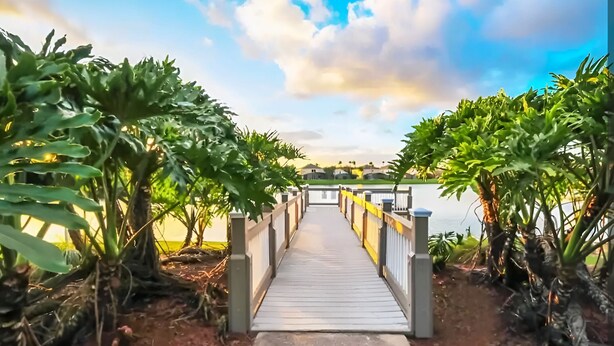 A wooden pathway leading to a building with a view of the sea.