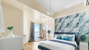 A modern bedroom with a large bed, a hanging chair, a view of the sea, and a marble wall. - All Inclusive VIP Celeb 5 Star Resort Pool Spa Gym (Parañaque)