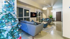 A modern living room with a large blue sofa, a coffee table, and a Christmas tree. - All Inclusive VIP Celeb 5 Star Resort Pool Spa Gym (Parañaque)