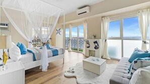 A bedroom with a bed, a nightstand, a white coffee table, a sofa, and a balcony with a railing. - All Inclusive VIP Celeb 5 Star Resort Pool Spa Gym (Parañaque)