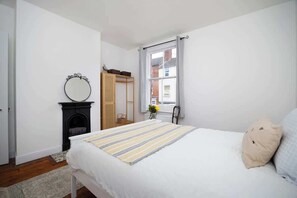 Una camera da letto con un letto, uno specchio, un camino, una finestra e una porta.