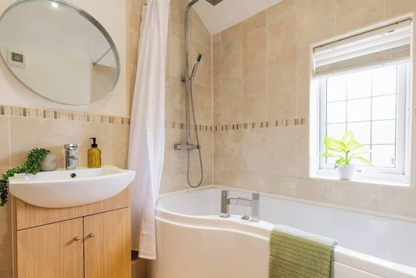 Ein Badezimmer mit Waschbecken, Spiegel, Dusche und Fenster.