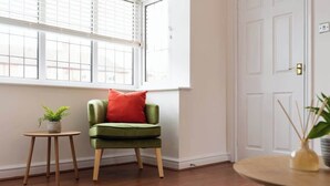 A room with a green chair, a small table with a plant, and a round table with a vase. - Spacious Home | Driveway Parking | Minutes from M1 (Nottingham)