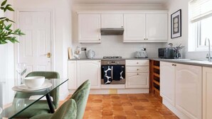 A compact kitchen with white cabinets, a stove, and a microwave. - Spacious Home | Driveway Parking | Minutes from M1 (Nottingham)