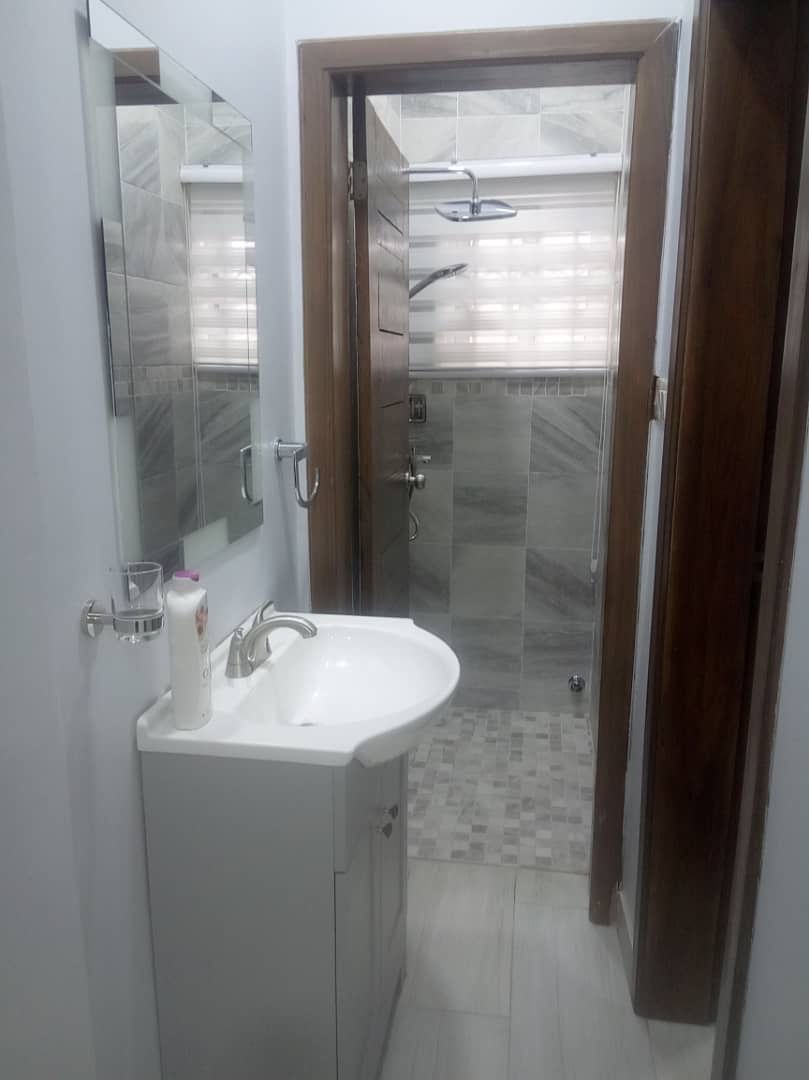 A bathroom with a white sink, mirror, and glass shower enclosure.