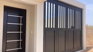 Un bâtiment moderne doté d’une porte noire et d’un grand portail de garage à lames verticales.