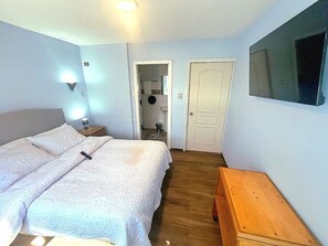 A bedroom with a bed, bedside table, and a TV on the wall. - Hotel Nova Vida (Concepción)