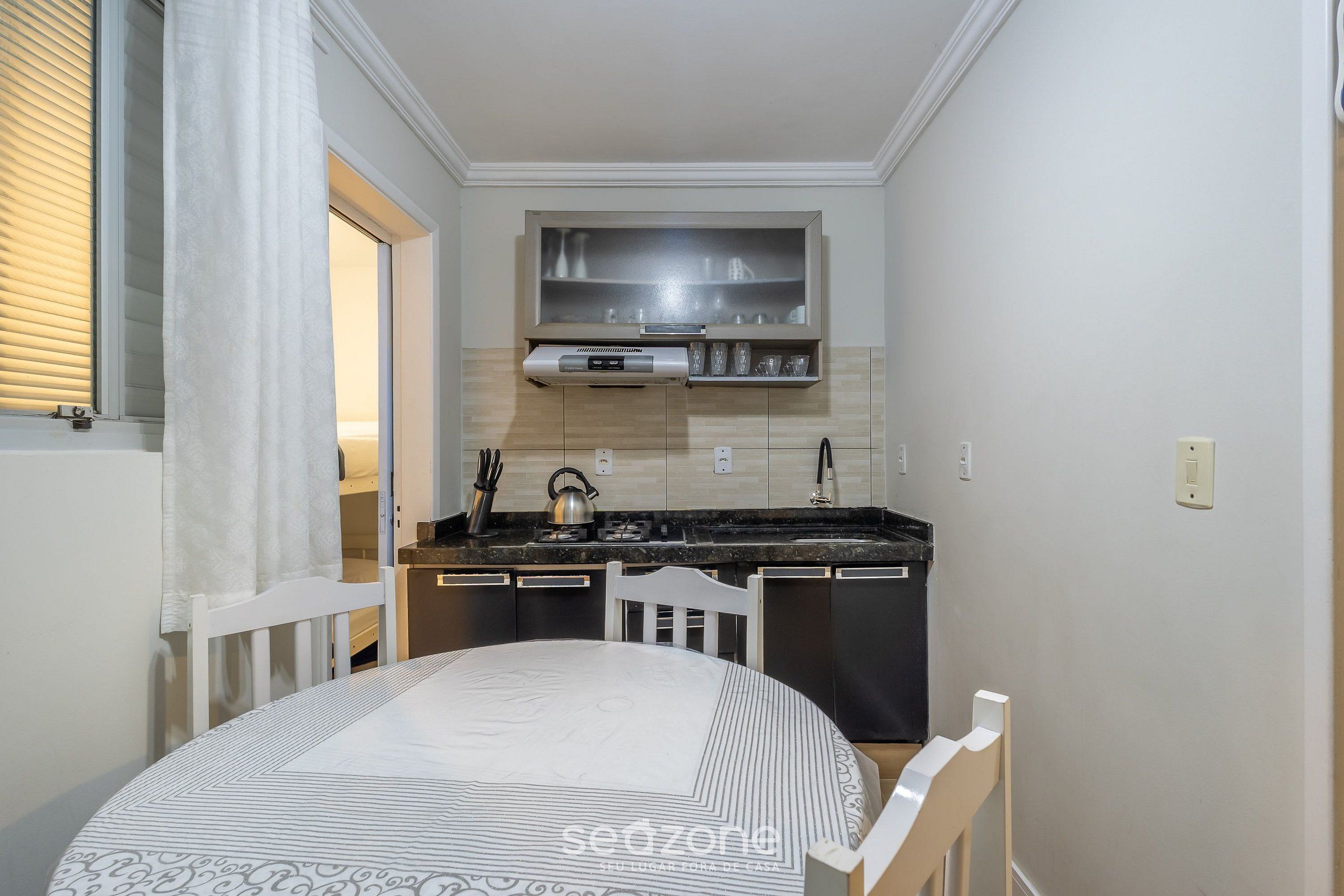 A compact kitchen with a stove, sink, and a small cabinet above the counter.