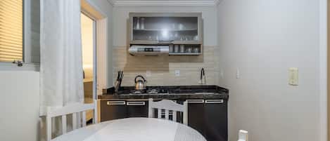 A compact kitchen with a stove, sink, and a small cabinet above the counter.