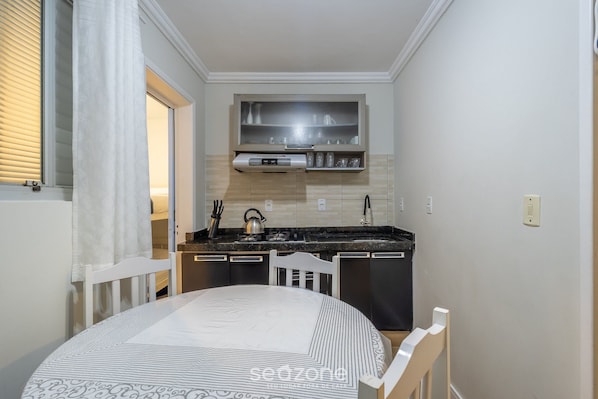 A compact kitchen with a stove, sink, and a small cabinet above the counter.