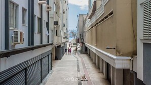 Une ruelle étroite en milieu urbain, bordée de bâtiments des deux côtés, avec des unités de climatisation apparentes, un escalier visible et un passage piétonnier.