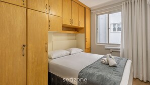 Une chambre à coucher avec un lit, une armoire en bois et une fenêtre avec des rideaux.