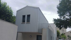 Un edificio moderno con techo plano, un pequeño balcón y una puerta.