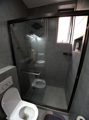 A modern bathroom with a glass-enclosed shower, a toilet, and a sink. - Gratia Residence (Kigali)