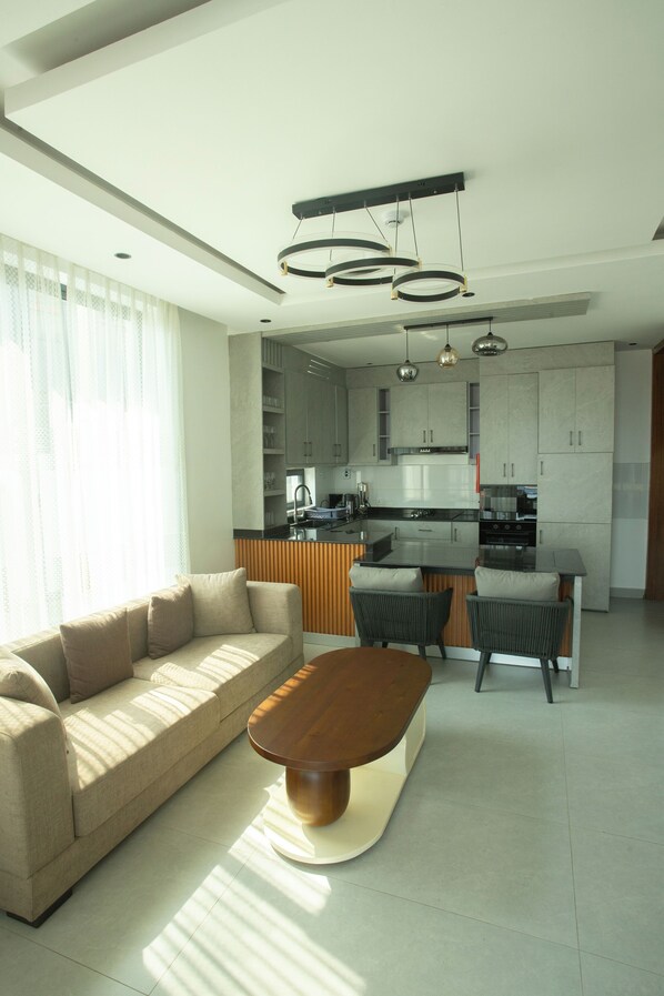 A modern kitchen with a central island, built-in cabinets, and pendant lighting. - Gratia Residence (Kigali)