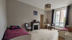 A bedroom with a bed, a desk, a chair, a fireplace, and a window with a view. - Bright apartment with private beach access (Saint-Lunaire)