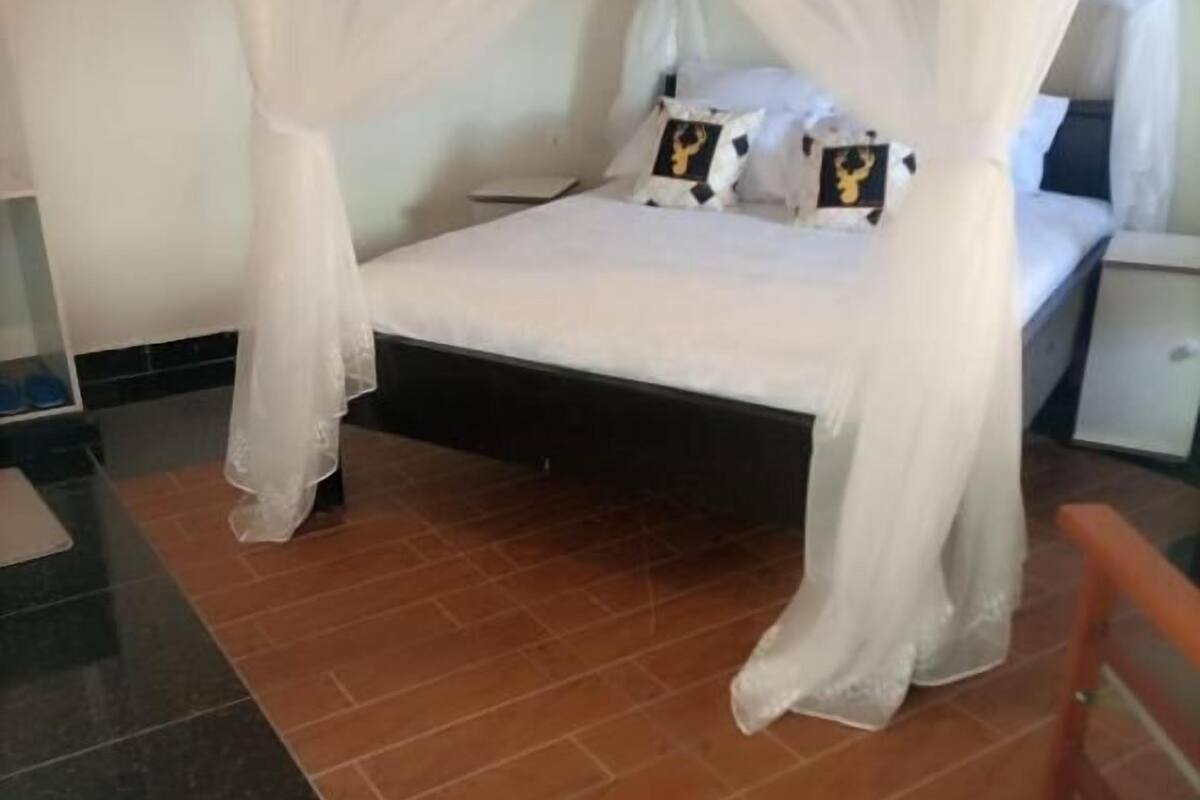 Uma cama com dossel branco, uma mesa de cabeceira e uma cadeira.