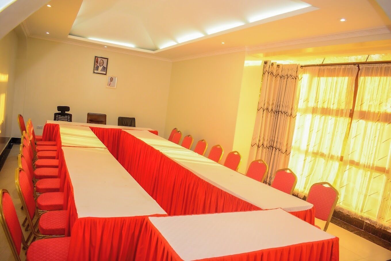 A conference room with a long table, red chairs, and a large window with curtains.