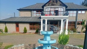 A fountain with a multi-tiered design in front of a building with a brick facade and a balcony. - OLOIRIEN HOTEL & RESORT (Narok)