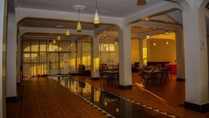 A spacious hotel lobby with a long reflective floor, multiple seating areas, and hanging pendant lights. - OLOIRIEN HOTEL & RESORT (Narok)
