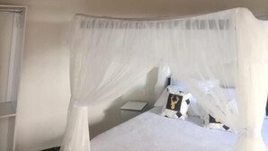 A room with a bed under a woven ceiling, a bedside table, and a window with curtains. - OLOIRIEN HOTEL & RESORT (Narok)