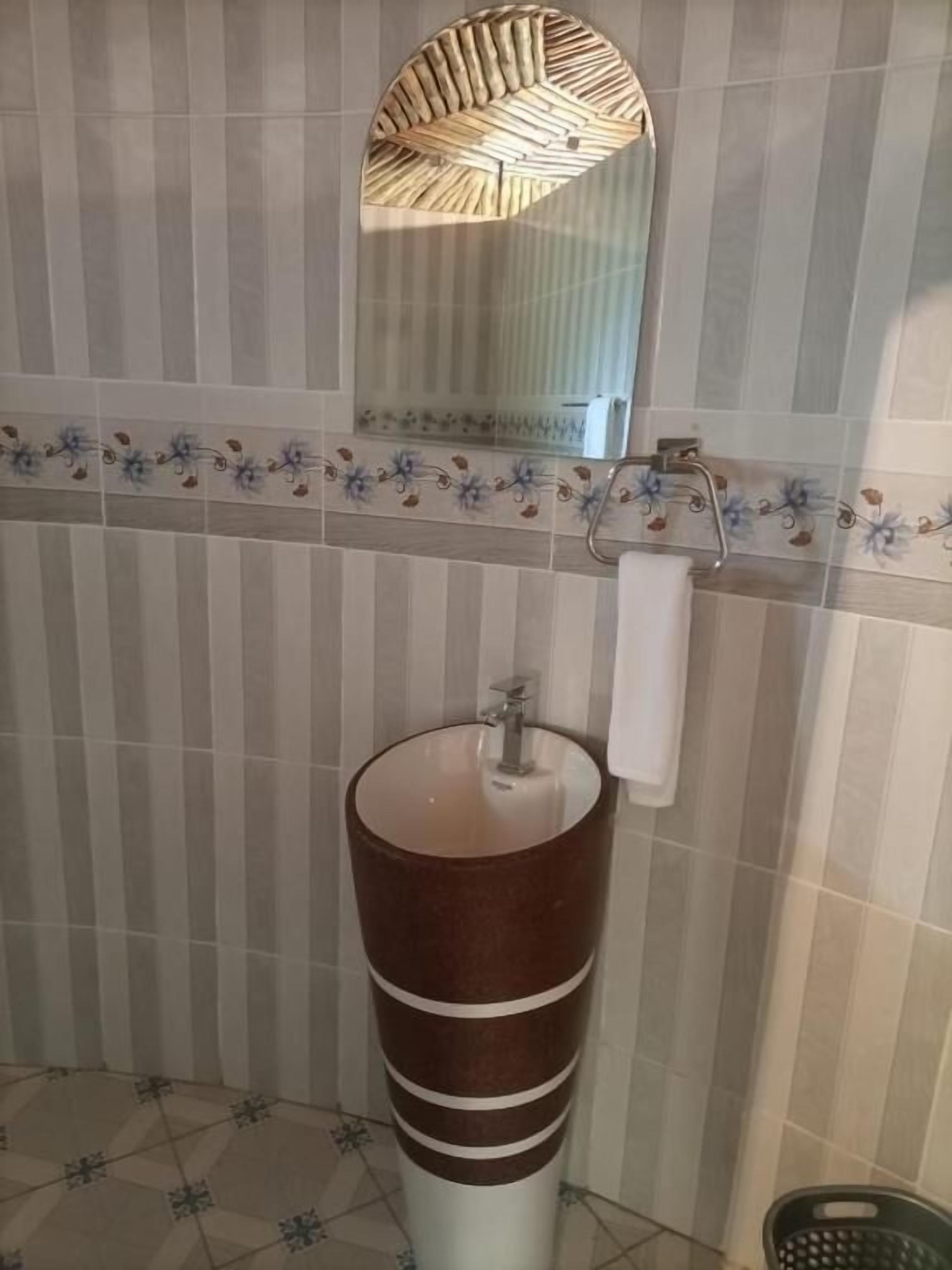 A bathroom with a round sink, a towel rack, and a mirror with a wooden frame.