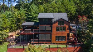 A multi-story log cabin with a deck and a large window on the second floor.