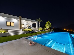 Ein moderner Poolbereich im Freien mit einem klaren, blauen Pool, einem Rettungsring und einer gut beleuchteten Terrasse mit Sitzgelegenheiten.