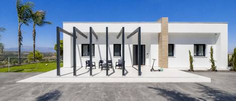 Een modern huis met een patio, buitenmeubels en uitzicht op het landschap.