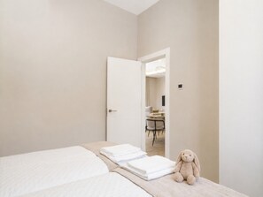 Een hotelkamer met een bed, een stoel, een tafel en een knuffel.
