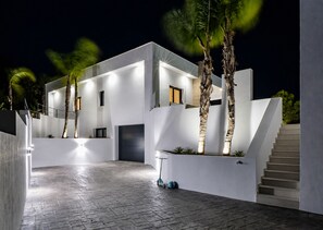 Une maison moderne dotée d’un vaste patio, d’un escalier et de palmiers.