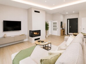 Un salon moderne doté d’un téléviseur à écran plat, d’une cheminée, d’un canapé et d’un coin repas.