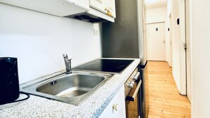 A kitchen with a stainless steel sink, a stove, and white cabinets. - Beautiful & Lovely Stay | Prime Spot by Belvedere (Vienna)