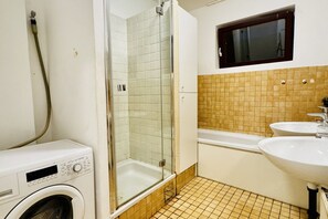 Ein Badezimmer mit Waschmaschine, Duschkabine, Badewanne und zwei Waschbecken.