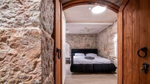 Un dormitorio de paredes de piedra con cama, puerta de madera y pared de piedra.