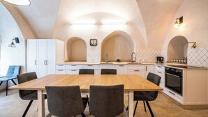 Una cocina moderna con una mesa y sillas de madera, armarios blancos y un horno empotrado.