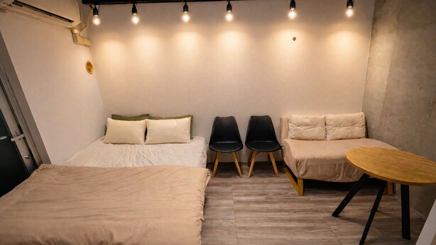 A compact room with a bed, two chairs, a small table, and a sofa.