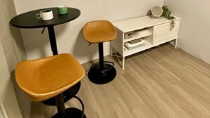 A small, modern room with a round table and two chairs, a white cabinet, and a hanging plant.