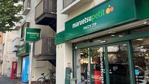 A storefront with a green awning and a sign reading "maruetsu petit".