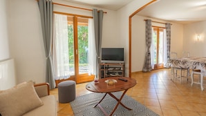 Una sala de estar con sofá, mesa de centro, televisión y un comedor con mesa y sillas.