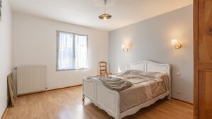 Un dormitorio con cama, ventana, radiador y lámpara de pared.
