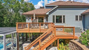 Une maison à deux étages dotée d’une terrasse, d’une piscine et d’un patio couvert.