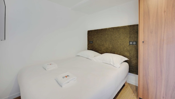 A hotel room with a bed, pillows, a wooden headboard, and a wooden wardrobe. - Pleasant and Bright apt - 1bd/2p - Near Paris (Aubervilliers)