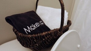 A wicker basket with a towel labeled "Makeup" on a white toilet. - 3BR Basement Apartment Close to CU (Central)