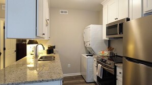 A kitchen with white cabinets, a granite countertop, a stainless steel refrigerator, a microwave, an oven, and a dishwasher. - 3BR Basement Apartment Close to CU (Central)